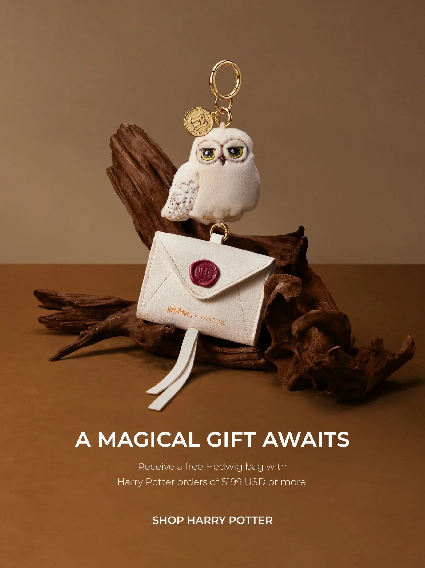 White Hedwig owl charm and envelope pouch on driftwood, with text 'A Magical Gift Awaits'